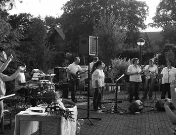 Band und Chor beim Gottesdienst im Freien, davor der geschmückte Altartisch