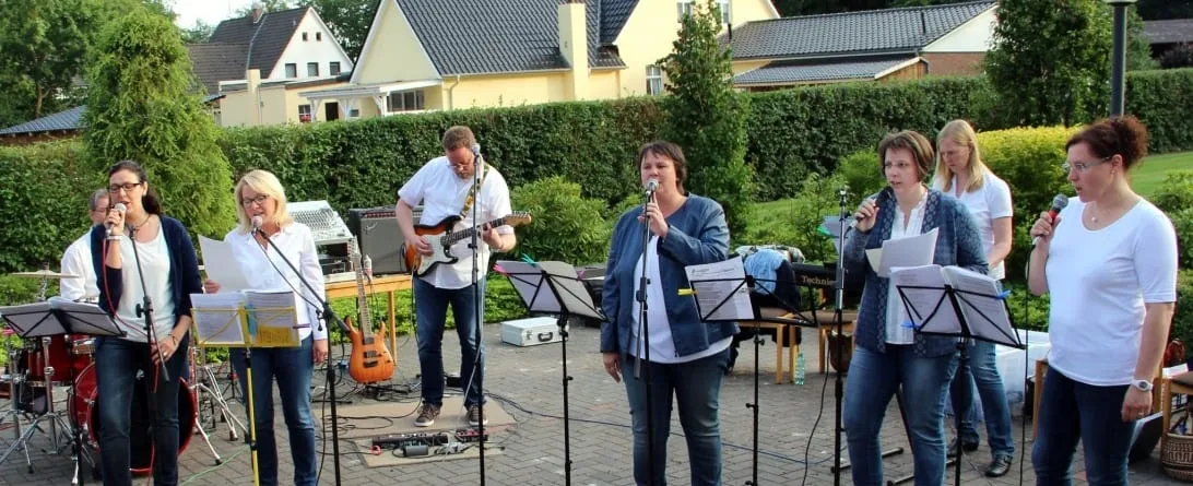 Band mit Sängerinnen beim Gottesdienst im Freien, dahinter Wohnhäuser