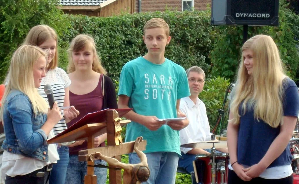 Jugendliche mit Mikrofon und Textblättern am Lesepult beim Gottesdienst im Freien