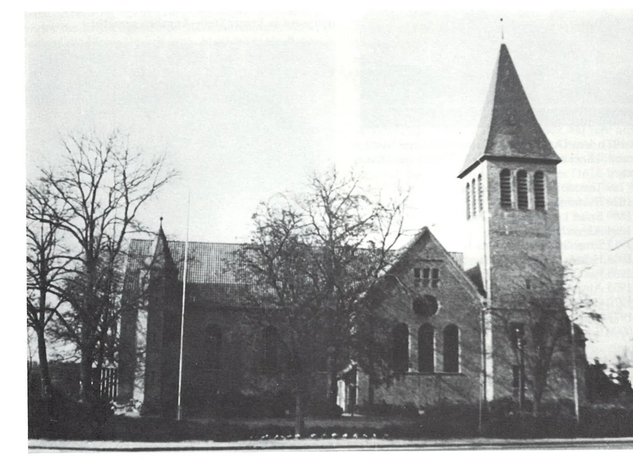 Schwarz-Weiß-Foto der Pfarrkirche St. Johannes Baptist in Markhausen mit hohem Turm, davor kahle Bäume.