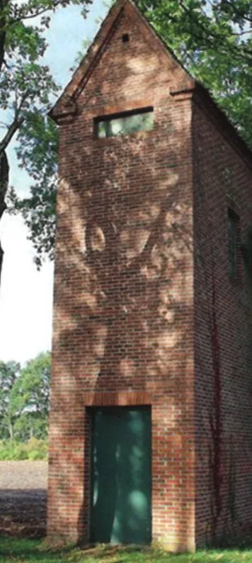 Der Transformatorturm: schmaler Backsteinturm mit Satteldach und grüner Stahltür.