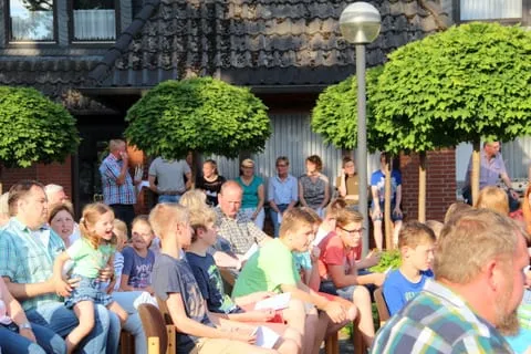 Publikum auf Stühlen beim Gottesdienst im Freien vor einem Wohnhaus