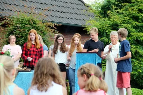 Jugendliche mit Kerzen beim Gottesdienst im Freien, daneben der Geistliche mit Mikrofon