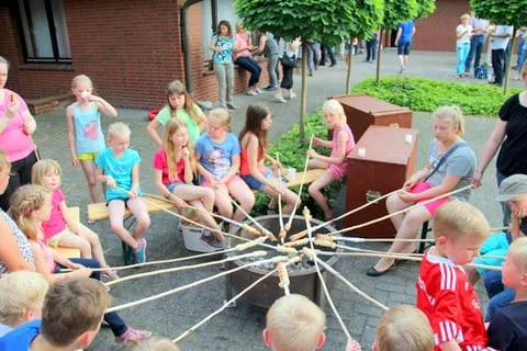 Kinder backen Stockbrot rund um eine Feuerstelle