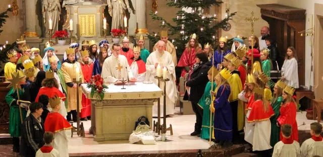 Sternsinger in bunten Gewändern rund um den Altar beim Aussendungsgottesdienst