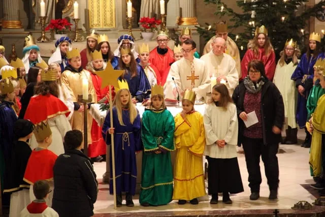 Sternsinger mit Kronen und Sternenstab, dahinter die Geistlichen am Altar