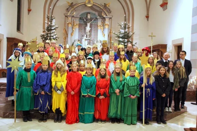 Große Sternsingergruppe in bunten Gewändern vor dem Altar