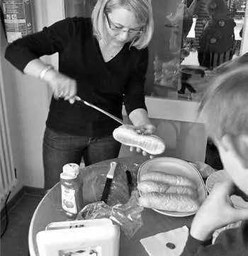 Eine Helferin reicht nach der Andacht ein Würstchen im Brötchen